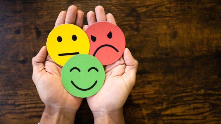 to hænder holder tre smileyer, der repræsenterer hvert sit humør